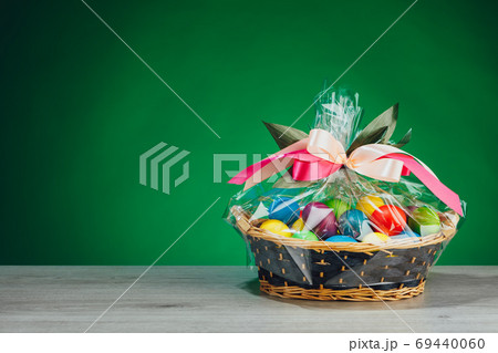Easter gift basket with multicolor eggs, green background 69440060