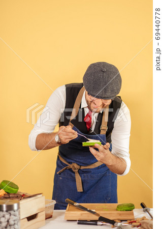 Cook preparing burger adding the sauce on green bun. Cook preparing burger adding the sauce on green bun. 69440778