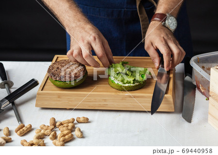 Chef adds basil on burger cooking hamburger concept Chef adds basil on burger cooking hamburger concept 69440958