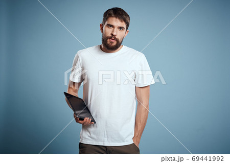Energetic man with a touch tablet on a blue background in a white t-shirt cropped view 69441992