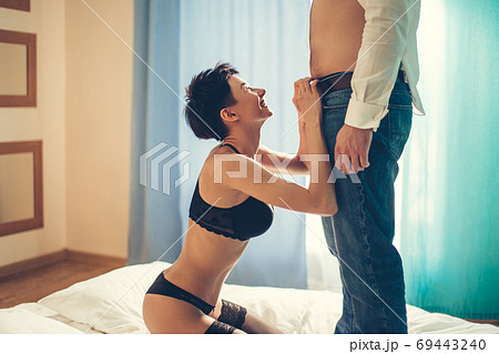 Attractive woman unzipping man jeans over black background 69443240