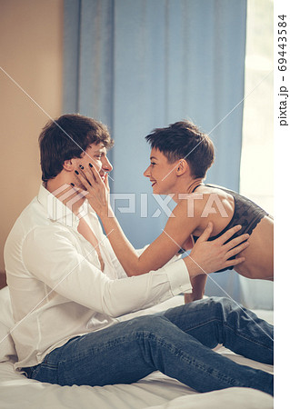Real love. Young hipster with beard and attractive woman resting at home while sitting on bed Real love. Young hipster with beard and attractive woman resting at home while sitting on bed 69443584