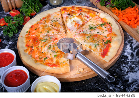 Salmon Seafood Pizza on a Black table with ingredients around 69444239