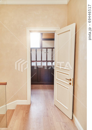 Opened white door to the home library with wooden balustrade. Classic style white door 69446517