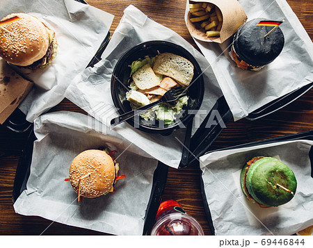 Burgers with vegetables and fries on a wooden board, top view. 69446844