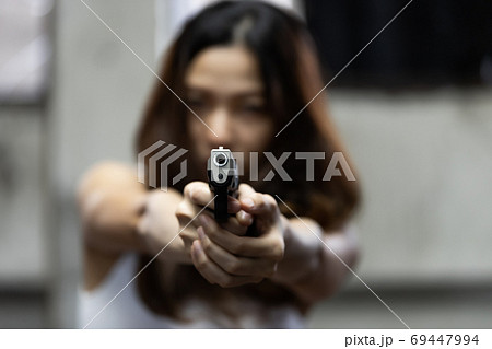 Woman aiming a gun at abandoned house background 69447994