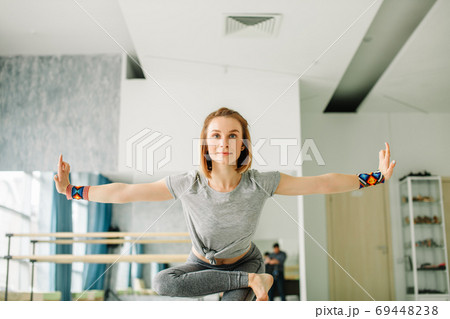 Woman doing balancing exercises during a yoga workout in well lit gym Woman doing balancing exercises during a yoga workout in well lit gym 69448238