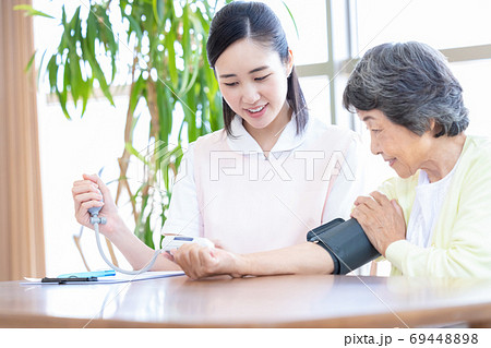 シニア女性と介護士　血圧を測る介護士 69448898