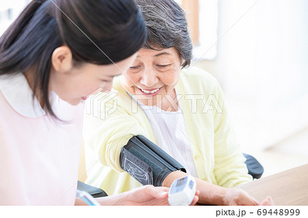 シニア女性と介護士　血圧を測る介護士 69448999