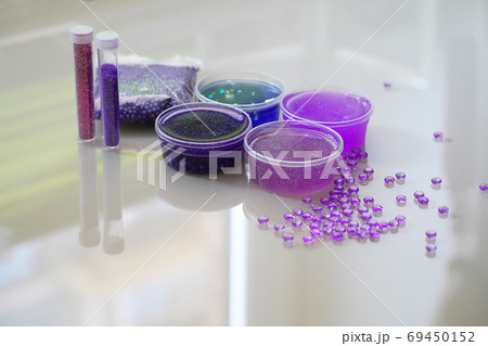 Defocused lilic, violet, blue slimes inside plastic boxes.  69450152