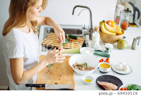Woman making kebabs from meat and vegetable on chopping board in kitchen Woman making kebabs from meat and vegetable on chopping board in kitchen 69450519