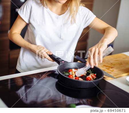 Cropped view of young happy housewife frying chicken meat for dinner 69450671