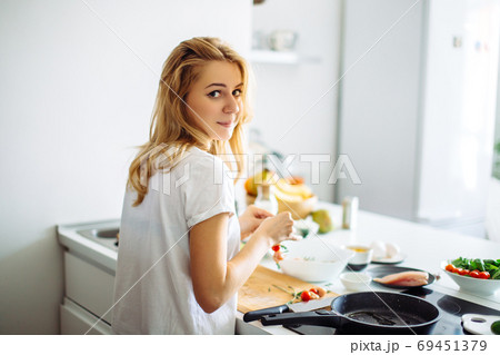 Young housewife making meal for linch in kitchen. rear view Young housewife making meal for linch in kitchen. rear view 69451379