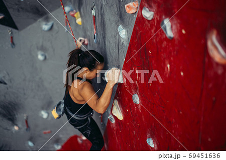 Beautiful young strong woman climbing on red artificial wall top view. 69451636