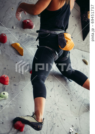 Close up of athletic woman practicing rock climbing on artificial wall indoors. Close up of athletic woman practicing rock climbing on artificial wall indoors. 69451737