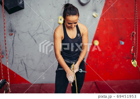 Woman climber tying rope in knot and preparing to climb. Climbing equipment 69451953