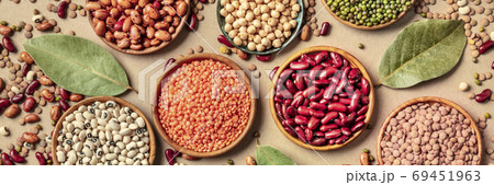 Legumes assortment, overhead panorama on a brown rustic background. Lentils, soybeans, chickpeas, red kidney beans, black-eyed peas, a vatiety of pulses Legumes assortment, overhead panorama on a brown rustic background. Lentils, soybeans, chickpeas, red kidney beans, black-eyed peas, a vatiety of pulses 69451963