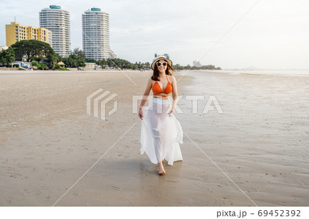 cheerful woman in bikini walking on sea beach 69452392