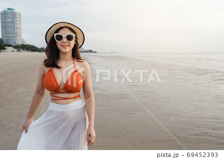 cheerful woman in bikini walking on sea beach 69452393