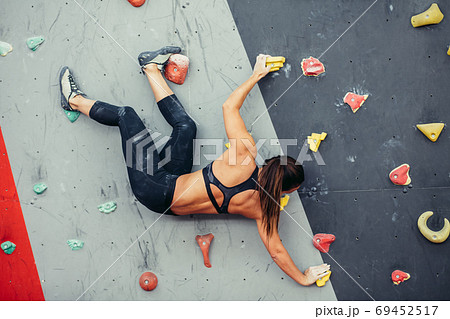 Beautiful young woman taking a big step up an artificial wall 69452517
