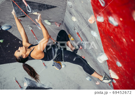 Woman reaching the top of artificial bouldering wall while exercising in gym. 69452672