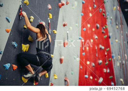 Sporty young woman training in a colorful climbing gym. Sporty young woman training in a colorful climbing gym. 69452768