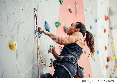 Beautiful young woman taking a big step up an artificial wall Beautiful young woman taking a big step up an artificial wall 69452829