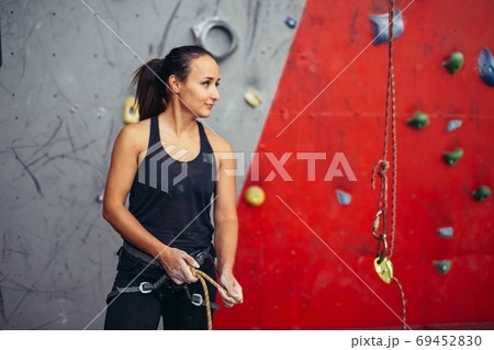Woman climber tying rope in knot and preparing to climb. Climbing equipment Woman climber tying rope in knot and preparing to climb. Climbing equipment 69452830
