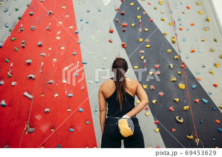 Sportswoman looking at climbing wall in gym Sportswoman looking at climbing wall in gym 69453629