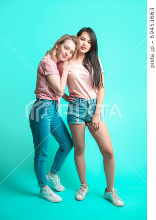 eenage girlfriends, caucasian woman and Asian woman - isolated on blue background eenage girlfriends, caucasian woman and Asian woman - isolated on blue background 69453663