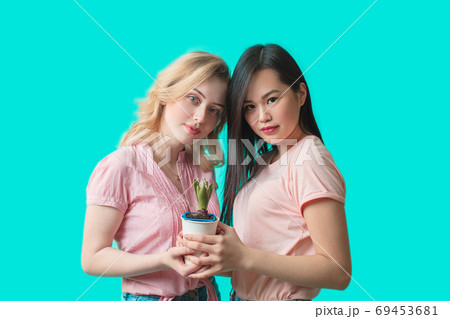 Couple of female florist holding cactus in pot isolated on blue background Couple of female florist holding cactus in pot isolated on blue background 69453681