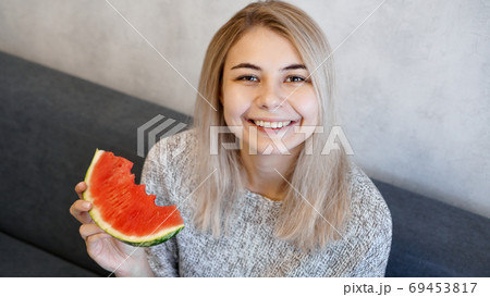Young attractive woman eating watermelon. Woman looking at camera and smiling Young attractive woman eating watermelon. Woman looking at camera and smiling 69453817
