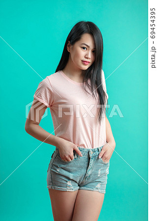 Cute asian woman posing at studio pastel blue background in shorts and sunglasses 69454395