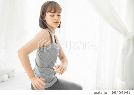 The woman after waking up in bedroom, Twisting the body from drowsiness and fatigue The woman after waking up in bedroom, Twisting the body from drowsiness and fatigue 69454945