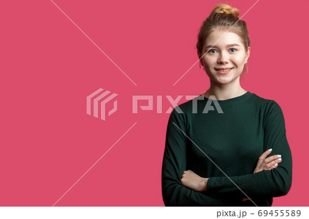 Pretty young woman with hair bun looking at camera with smile over pink Pretty young woman with hair bun looking at camera with smile over pink 69455589