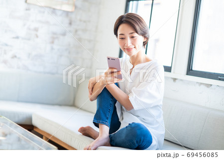 リビングでスマホを操作するミドルの女性 69456085