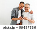 Happy two age generations men family old father embracing young grown adult son having fun enjoying using smart phone bonding watching funny social media video using mobile apps 69457536