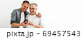 Happy two age generations men family old father embracing young grown adult son having fun enjoying using smart phone bonding watching funny social media video using mobile apps 69457543