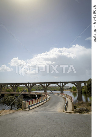 Road crossing a dam next to an old stone bridge for the railway 69459026