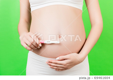 Close up of positive pregnancy test against pregnant woman's bel Close up of positive pregnancy test against pregnant woman's bel 69461604
