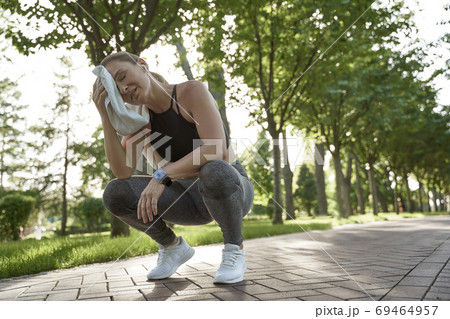 Working hard. Tired fitness woman in sportswear feeling exhausted after active morning workout in the city park. Sport and healthy lifestyle Working hard. Tired fitness woman in sportswear feeling exhausted after active morning workout in the city park. Sport and healthy lifestyle 69464957