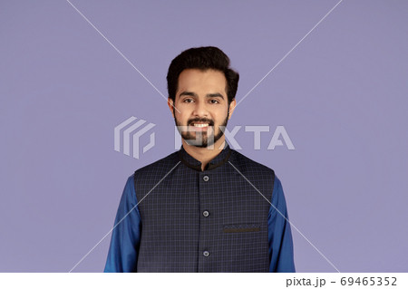 Handsome millennial man of Indian origin smiling on lilac background 69465352