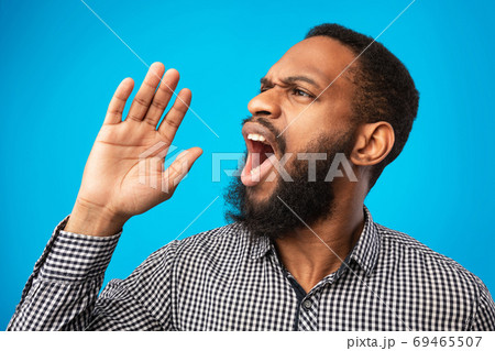 Black guy holding palm near mouth, screaming aside at copyspace 69465507