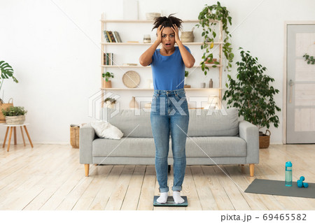 Woman Stressing Out About Gaining Weight Standing On Scales Indoor 69465582