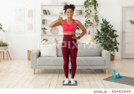 Fit African Woman Standing On Weight Scales Gesturing Thumbs-Up Indoor 69465649