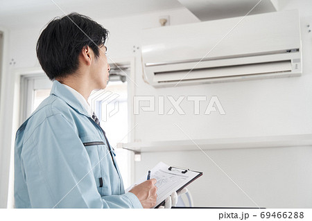 家庭用エアコンのチェックをする日本人男性電気工事士 69466288