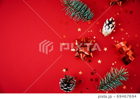 Christmas composition. Fir tree branches with xmas decoration and festive confetti on red background 69467694