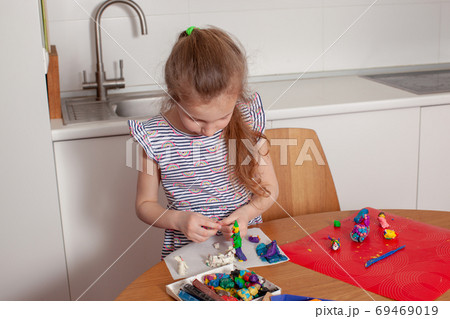 7 years old girl sculpts from plasticine. Close-up.  69469019