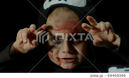 Halloween, angry girl with blood makeup on face. Kid dressed as scary skeleton, posing, making faces 69469366
