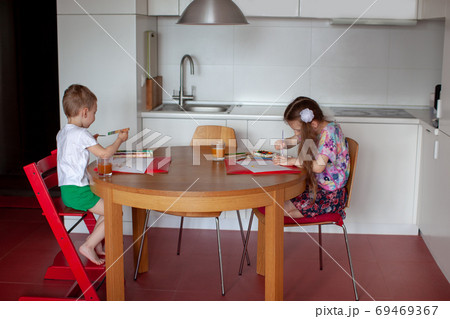 Seven year old girl and three year old boy paint. Modern kitchen interior. Seven year old girl and three year old boy paint. Modern kitchen interior. 69469367